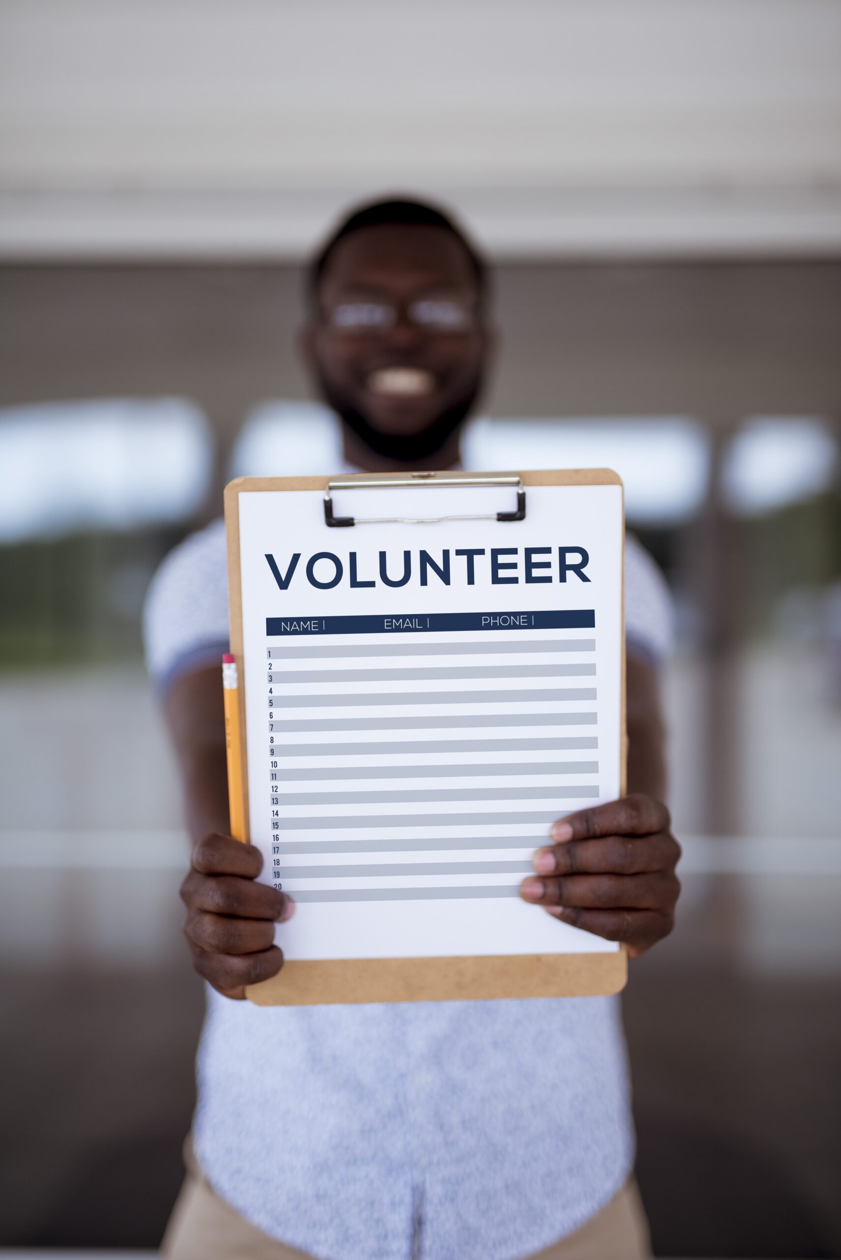 Vertical shot of a male holding up the volunteer sign up sheet with a blurred background